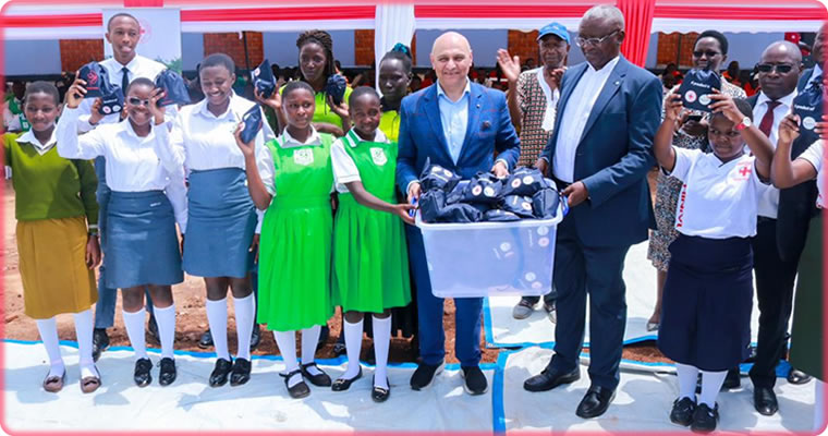 Robert Kwesiga, the secretary general of the Uganda Red Cross Society, and Dr. Nik Kotecha, the founder of the Randal Charitable Organization, pose for a photo alongside some of the invited students as they display some of the pads made at the Namakwa-based facility.