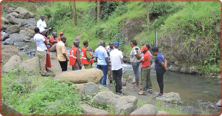 Emmanuel Ntale, manager of climate action and the environment at the Uganda Red Cross Society, and a group from the European Union Humanitarian Aid inspect a recently erected river gauge in Sironko region.
